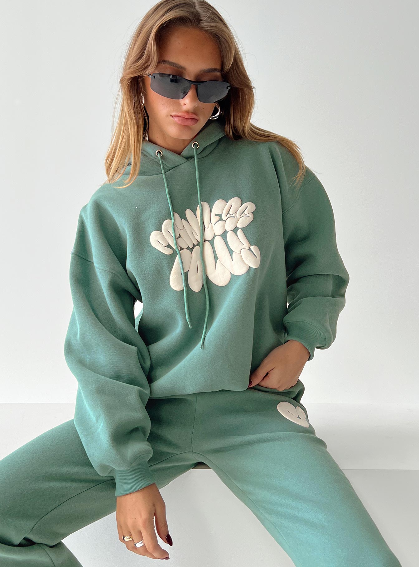 front view of model wearing Princess Polly Princess Polly Hooded Sweatshirt Bubble Text Sage / Eggshell regular 