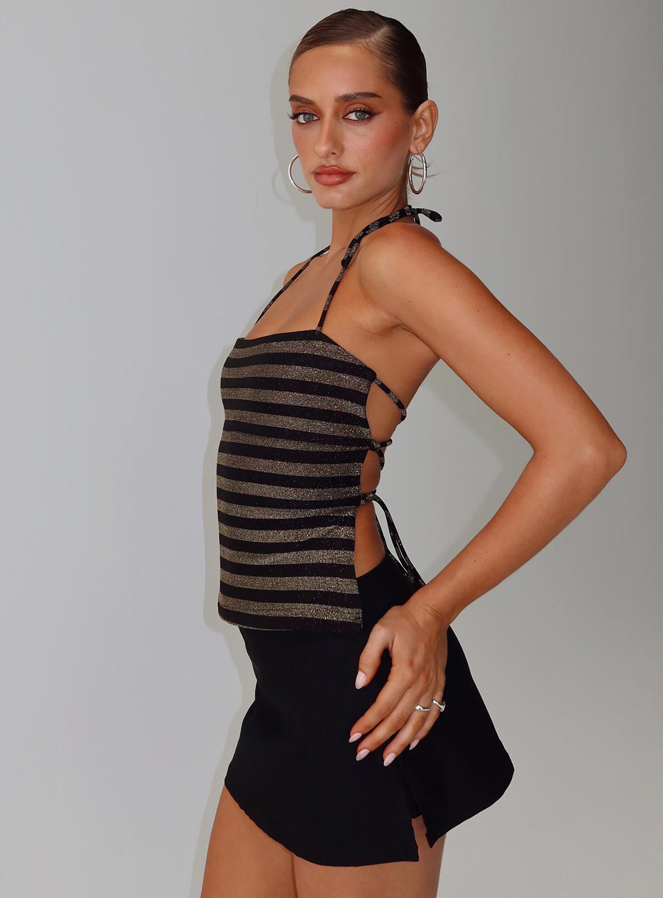 side view of model wearing Princess Polly The Player Backless Tie Neck Top Gold / Black Stripe Sleeveless Square Neck 
