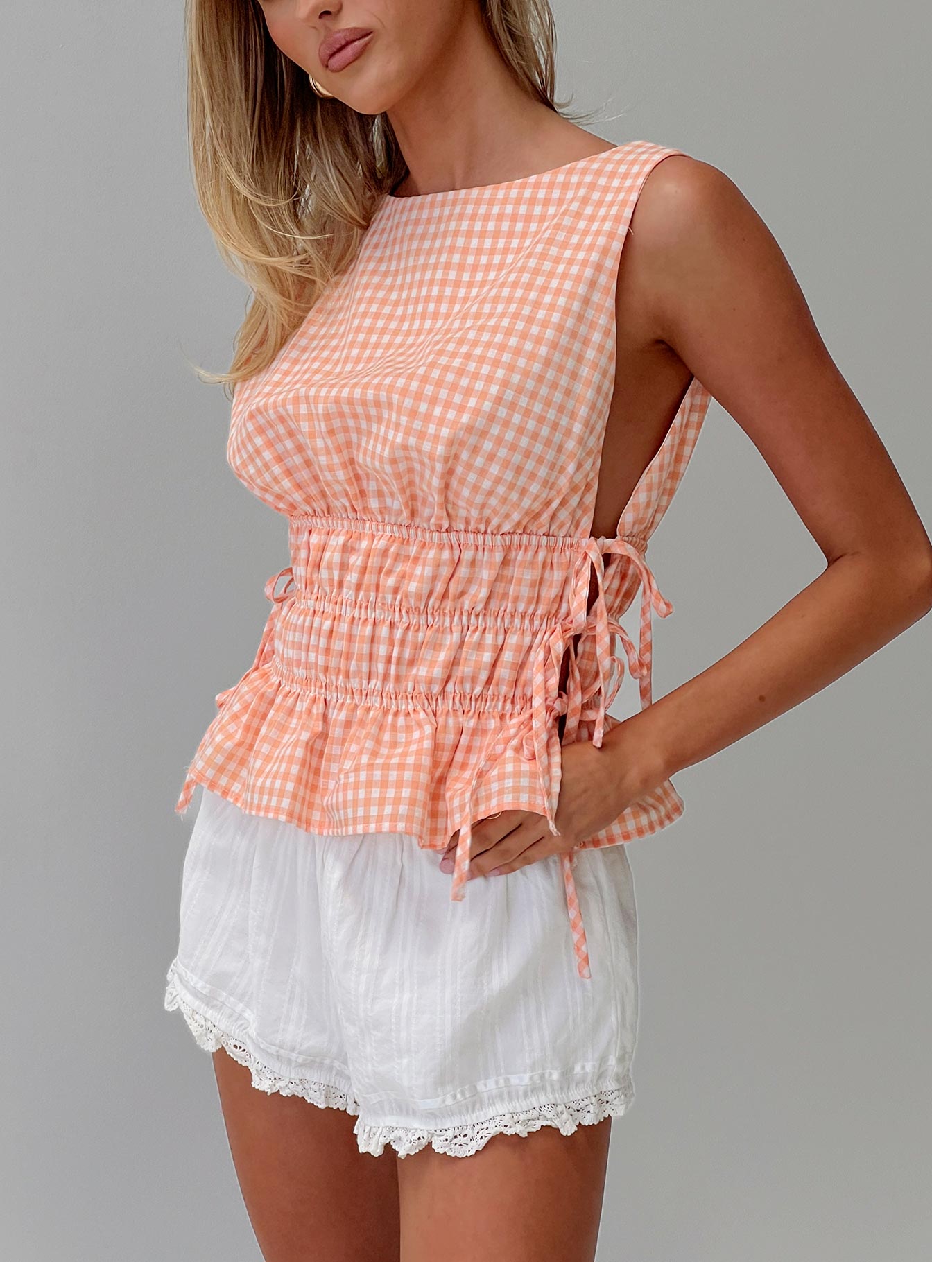 side view of model wearing Princess Polly Antiqued Tie Side Top Orange Check Sleeveless Boat Neck 