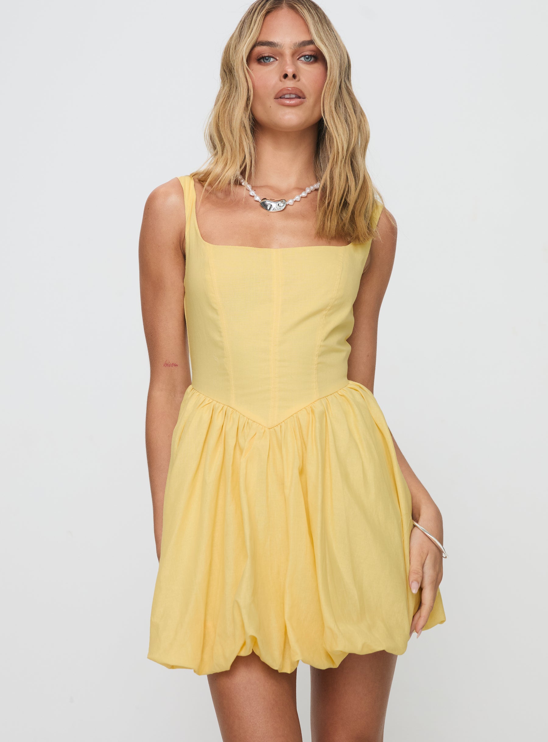 side view of model wearing Princess Polly Alcott Bubble Hem Mini Dress Lemon Square Neck 