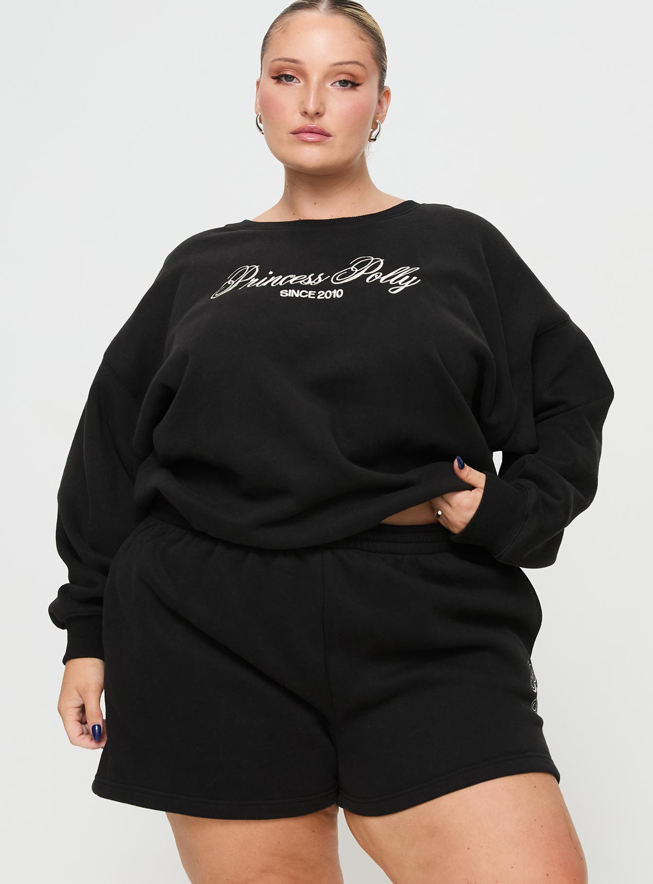 front view of model wearing Princess Polly Princess Polly Track Shorts Cursive Text Black Sand Curve High Waisted Shorts 