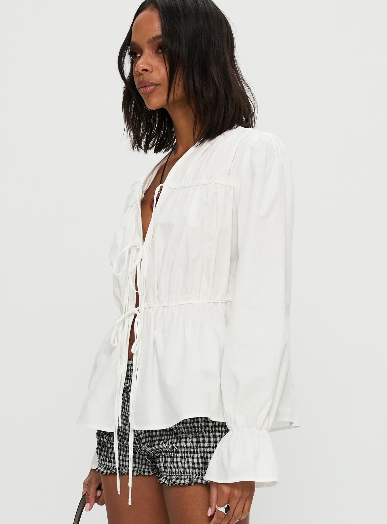 side view of model wearing Princess Polly Scarlotte Bow Tie Top White Full Sleeves V-Neck 