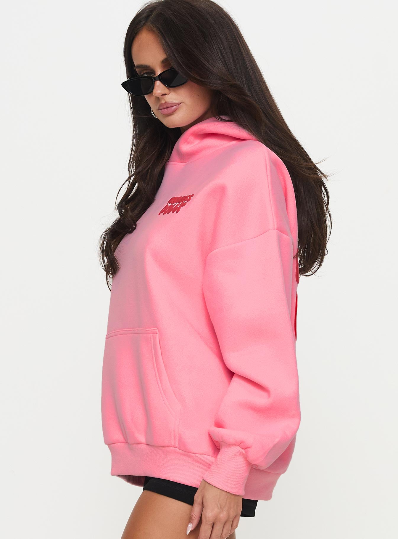 side view of model wearing Princess Polly Princess Polly Hooded Sweatshirt Bubble Text Pink / Red Long 