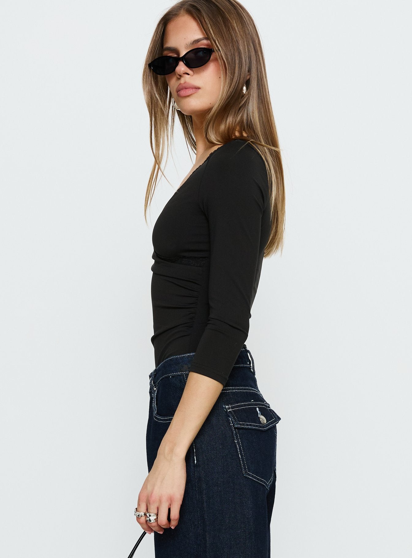 side view of model wearing Princess Polly Lyselle Wrap Detail 3/4 Sleeve Bodysuit Black Quarter Sleeve 