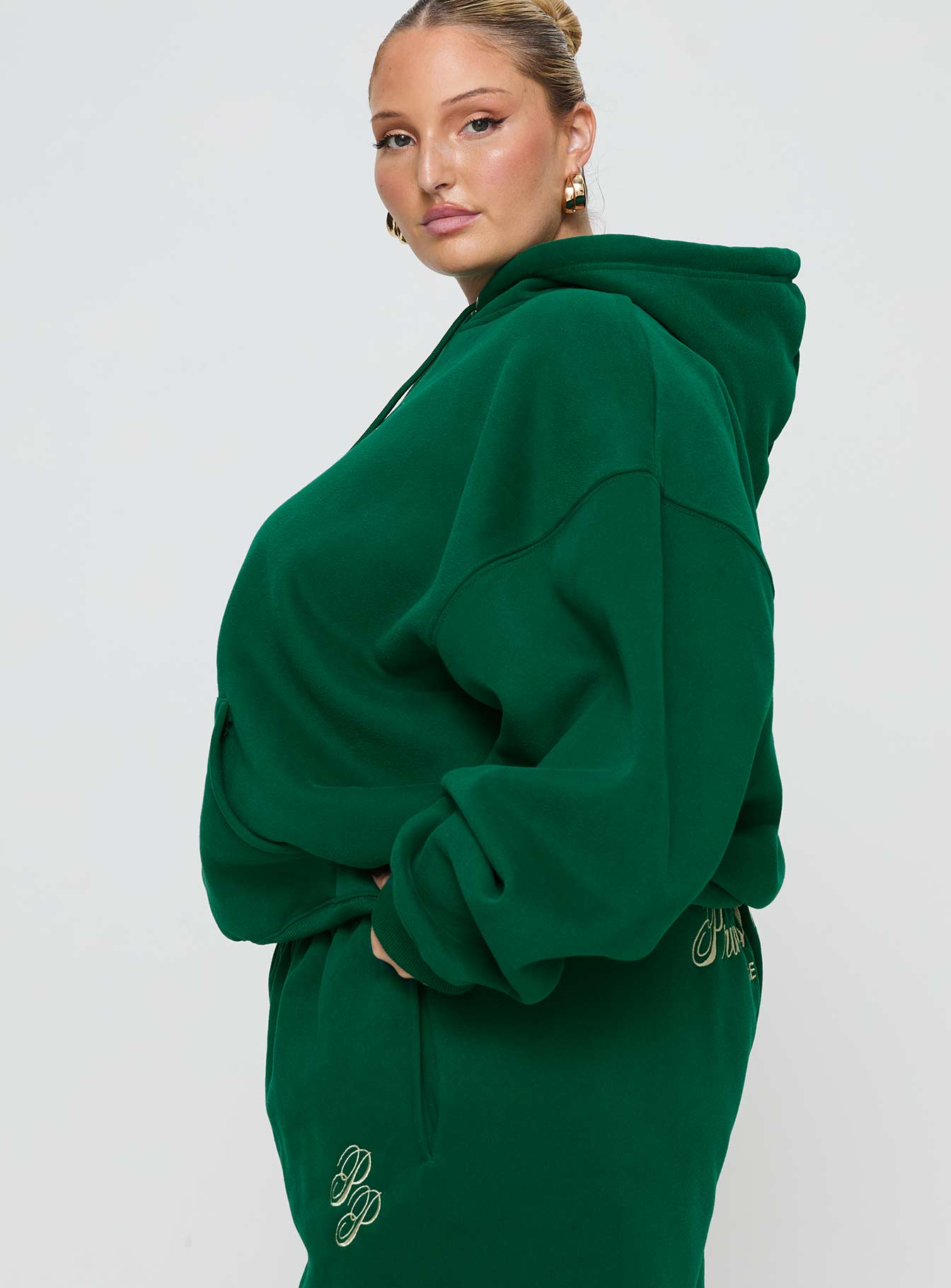 side view of model wearing Princess Polly Princess Polly Hooded Sweatshirt Script Green / Ivory Curve 