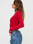 side view of model wearing Princess Polly Beller Long Sleeve Top Red Full Sleeves Asymmetric Neckline 