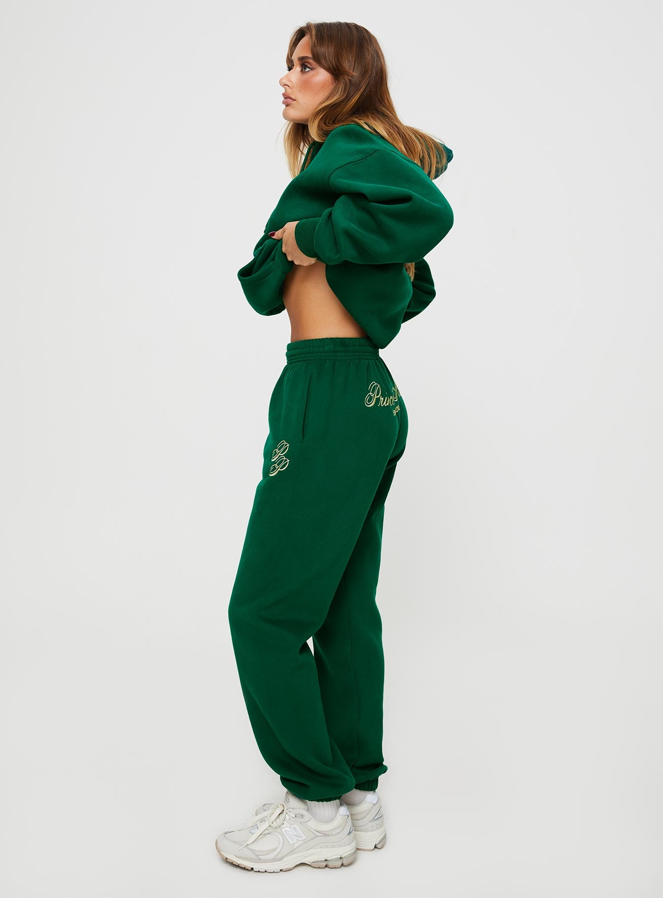 side view of model wearing Princess Polly Princess Polly Track Pants Script Green / Ivory High Waisted Pants 