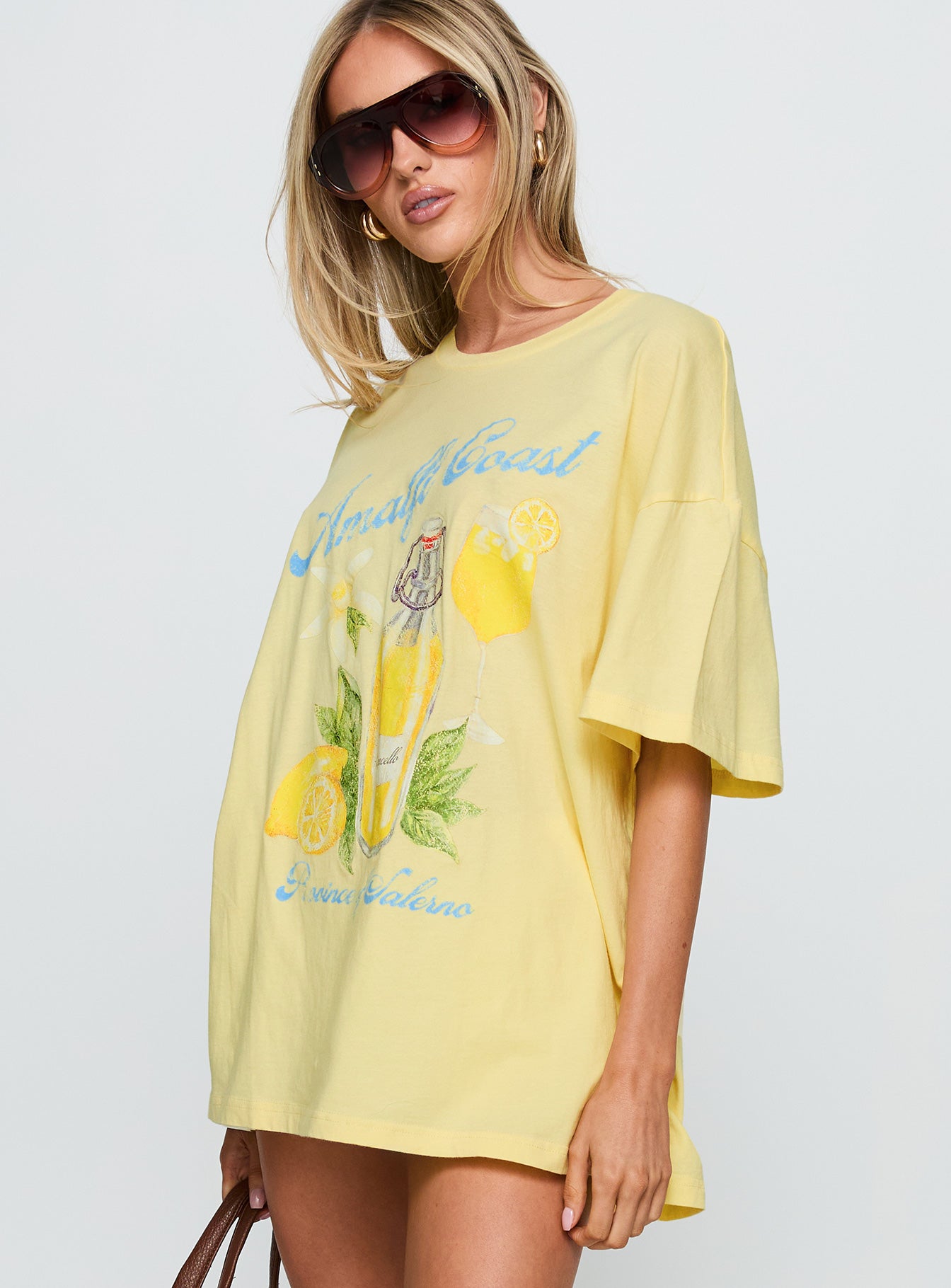side view of model wearing Princess Polly Amalfi Coast Oversized Graphic Tee Pastel Yellow Half Sleeves Crew Neck 