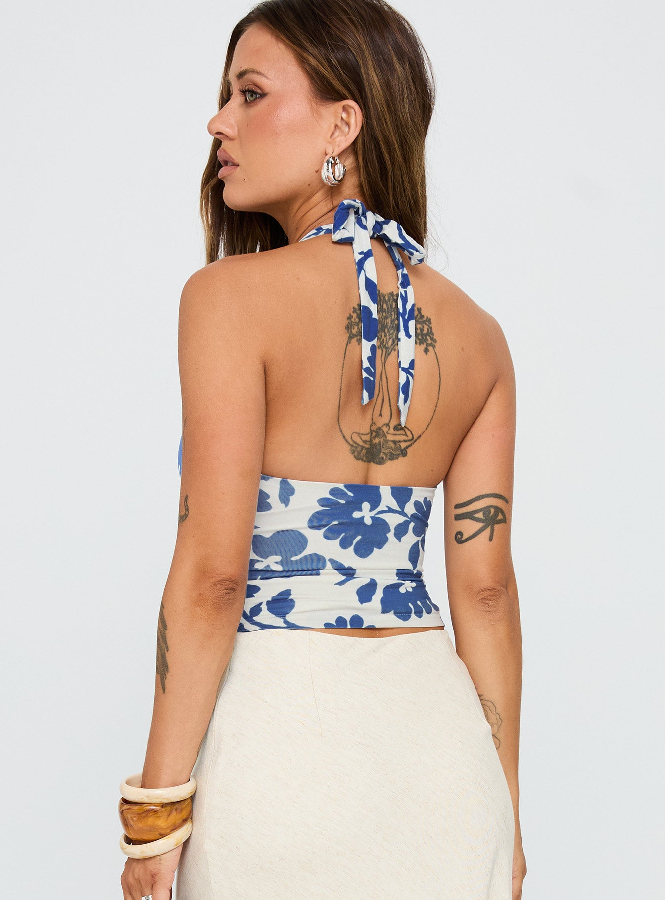 back view of model wearing Princess Polly Chilli Halter Top Blue Floral Sleeveless Plunger 