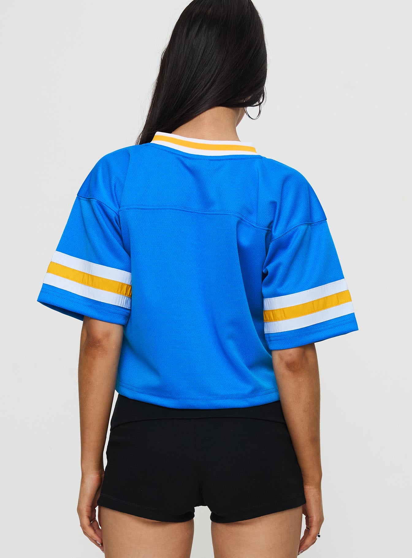 back view of model wearing Princess Polly UCLA Football Jersey Blue Half Sleeves V-Neck 