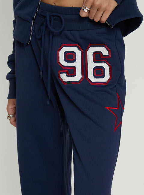 back view of model wearing Princess Polly Kari Distressed Patch Track Pant Navy Multi High Rise Pants 