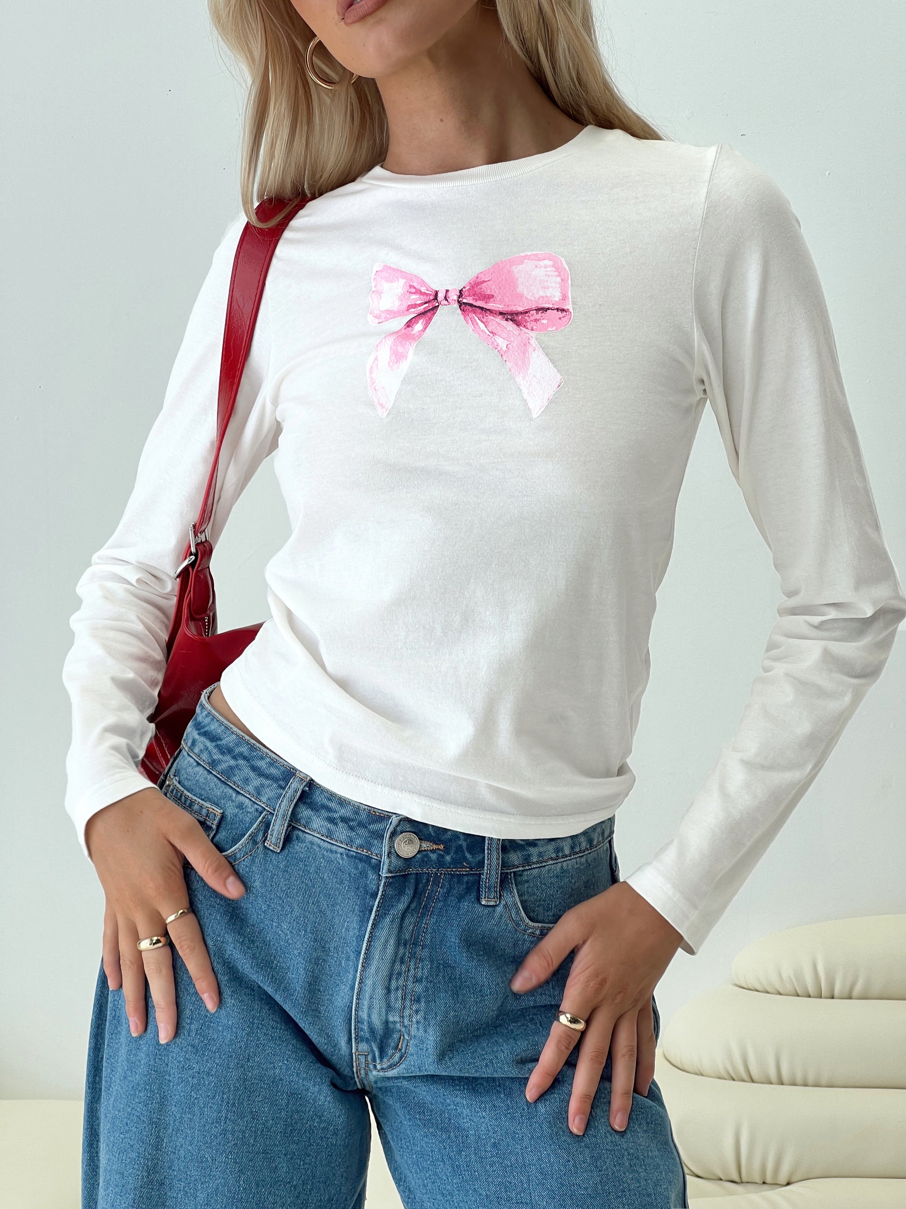 front view of model wearing Princess Polly Bow Baby Long Sleeve Top White Full Sleeves Full Sleeves Crew Neck Crew Neck 