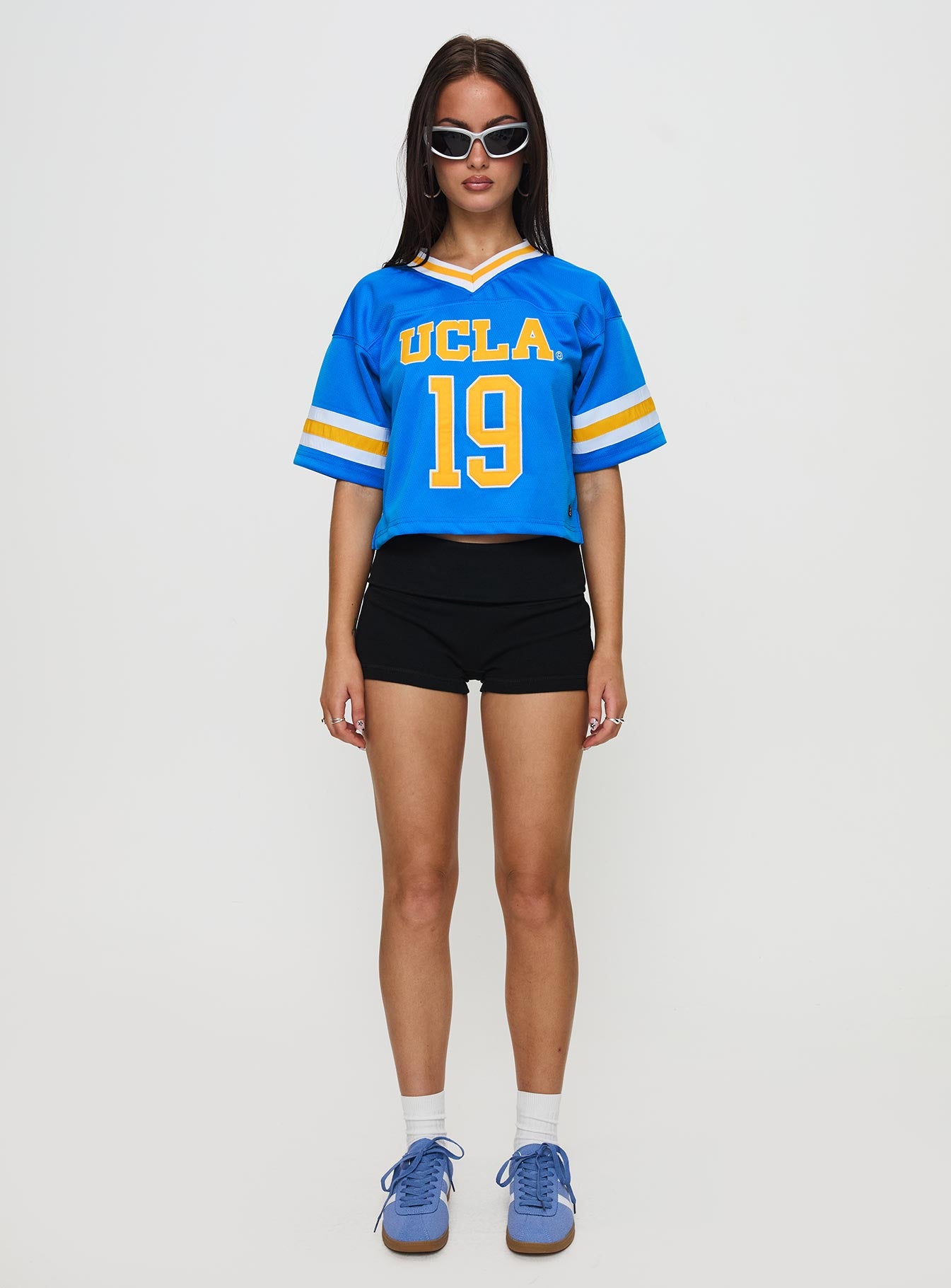 back view of model wearing Princess Polly UCLA Football Jersey Blue Half Sleeves V-Neck 