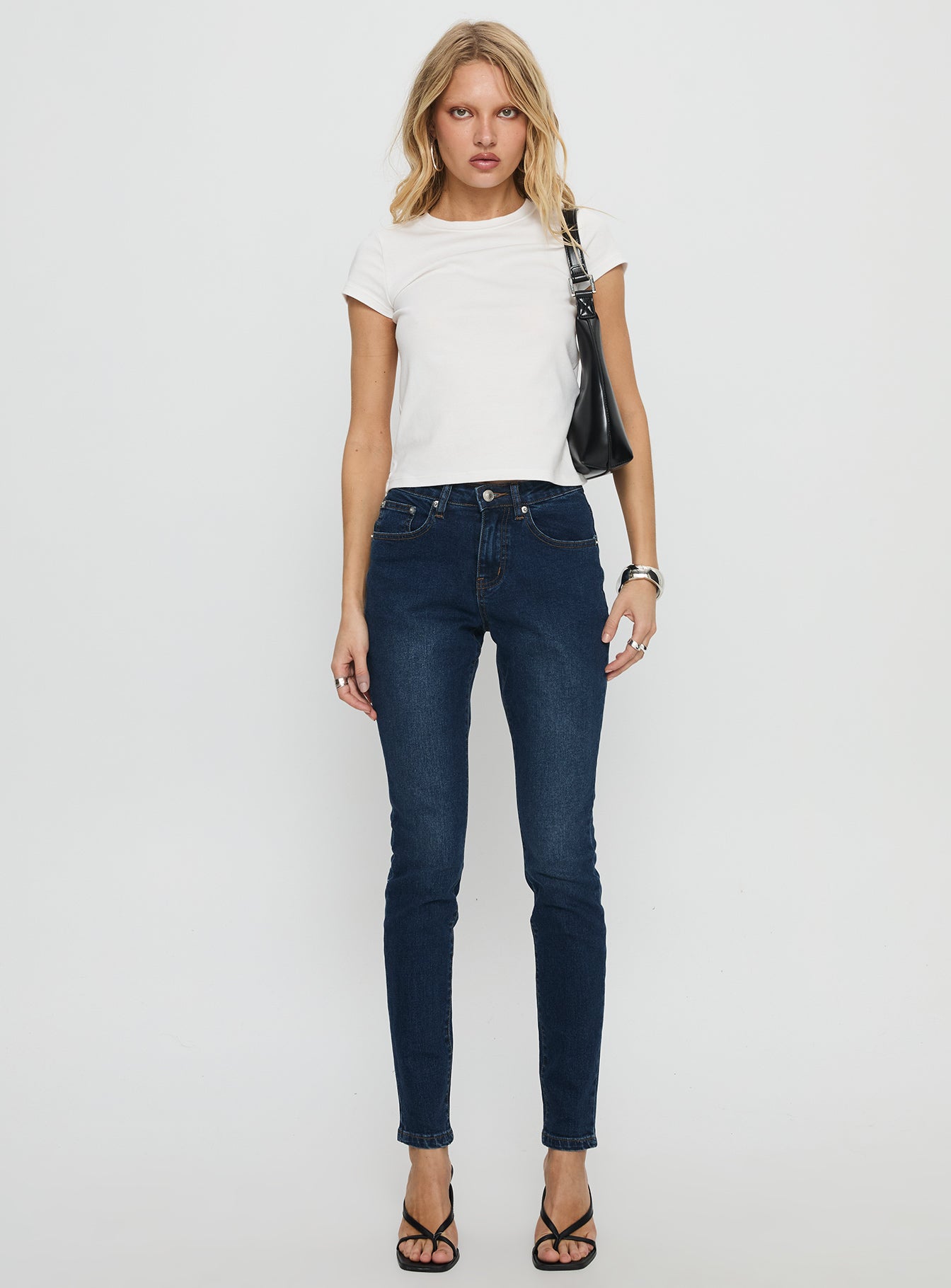 front view of model wearing Princess Polly Illyssa Mid Rise Skinny Jeans Mid Blue Wash Mid Rise Jeans 