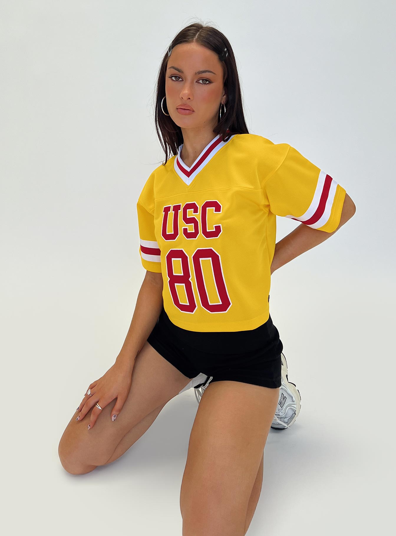 back view of model wearing Princess Polly USC Football Jersey Gold Half Sleeves V-Neck 