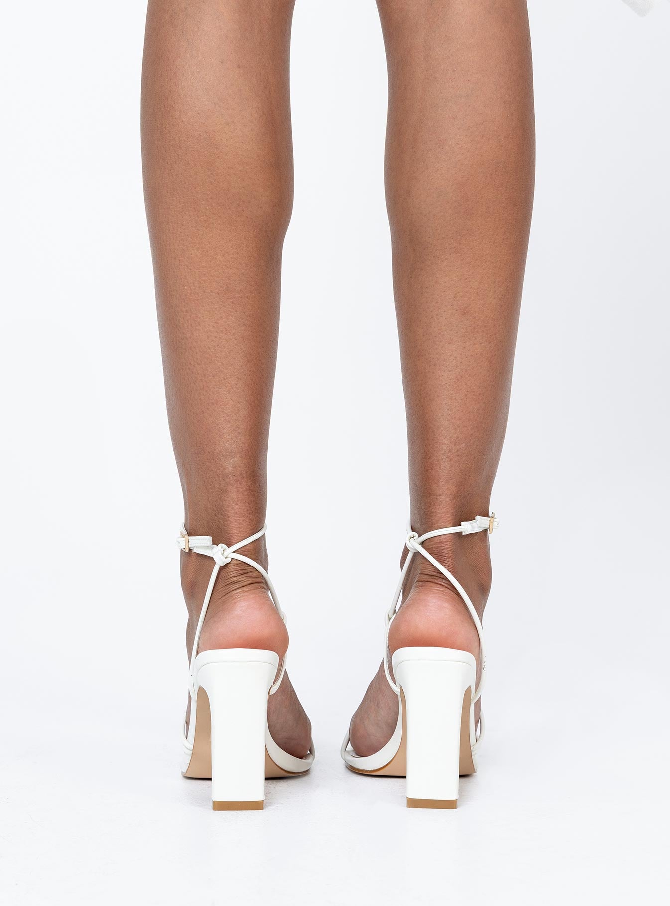White heels  Faux leather material  Thin strappy upper  Ankle strap  Gold-toned buckle fastening  Square toe  Shaved block heel  Padded footbed 