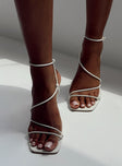 White heels  Faux leather material  Thin strappy upper  Ankle strap  Gold-toned buckle fastening  Square toe  Shaved block heel  Padded footbed 